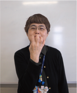 握った右手を顔の前に持ってくる写真