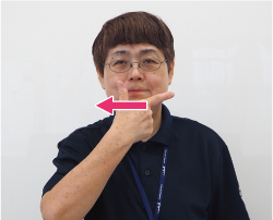 親指を立てて人差し指を口の端にあてる写真