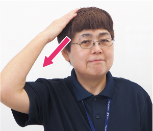 右手を頭に乗せて、下へ動かす写真