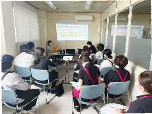 従業員が集まって椅子に座り、講師の話を聞いている写真