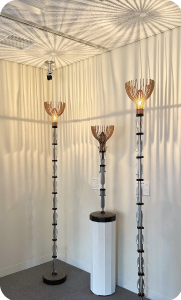 背の高いスタンドライトの花のように放射状に伸びた影が天井に投影されている写真