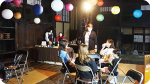 提灯のぶら下がる囲炉裏の間で、イスに座り飲食をしているお客さんの写真