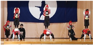 土台の人は四つん這い、その上に両手を頭上にあげた人が立ち、2人で組になって角兵衛獅子の技を披露している写真