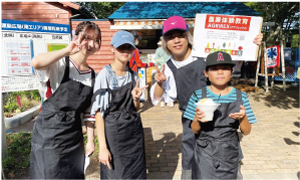 お揃いの黒いエプロンを付けた白根高校卒業生男女と南区内の小学生男女、4人の写真