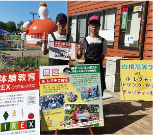 看板の前で並ぶ白根高校卒業生男子2人の写真