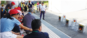 炎の描かれた的に向け消火器の水を命中させる児童の写真