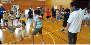 水に見立てたカラーボールをバケツに入れて運ぶこどもたちの写真