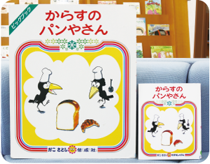 大きな絵本「からすのパンやさん」と通常のものの表紙を比較している写真