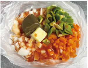 細かく切った野菜、焼き鳥、野菜ジュース、カレールウ、バターをポリ袋に入れた写真