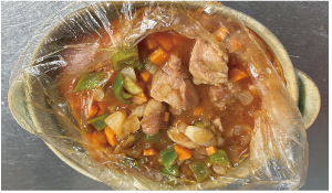 できあがったチキンカレーが入っているポリ袋の口を切り、袋のまま皿に乗せた写真