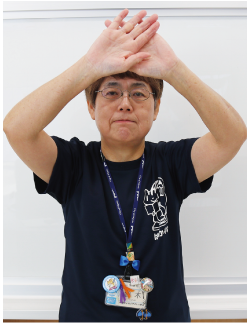 手話通訳者鈴木さんが両手の平を前に向け、頭の前で重ねている写真