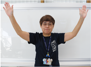 手話通訳者鈴木さんが頭の前で重ねた手を左右に広げた写真