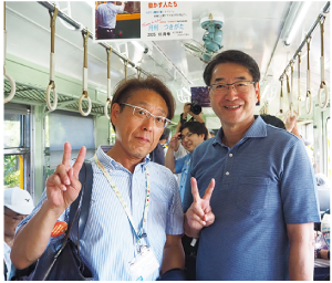 かぼちゃ電車内で、向かって左に長浜南区長、右に中原新潟市長が立ち、Ⅴサインで写っている写真