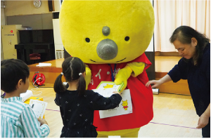 サイチョからプレゼントのレジャーシートを受け取る園児の写真