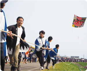 中ノ口川土手・白根側で大凧の引手が走り、大凧が揚げている写真