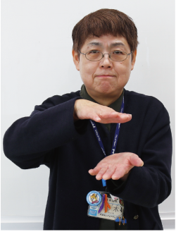 手話通訳者鈴木さんが少し間隔を空けて両手の平をうち側にし、その手を上下日広げている写真