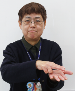 手話通訳者鈴木さんが片方の手の平に、手の甲を上にしてチョキにした手を乗せている写真