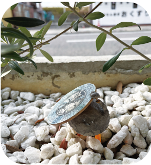 植え込みに佇む「凧マンホールさん」の写真