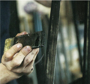 ハケを使い仏壇の材料に漆を塗っている写真