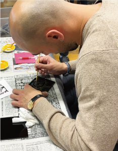 金箔を蒔いて、絵に金粉を定着させている写真