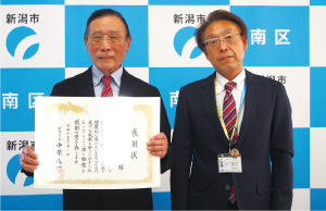 市長感謝状を胸の前に広げた「ふれあいパーク有願の里公園管理推進協議会」の代表と長浜区長が並んだ写真