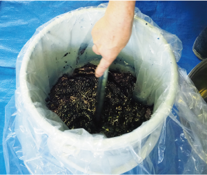 バケツにお湯と藍を入れ混ぜ合わせている写真