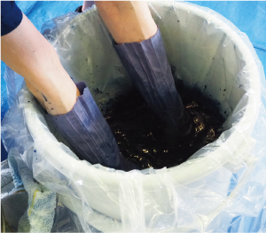 バケツの中にビニール袋をはめた手を入れている写真