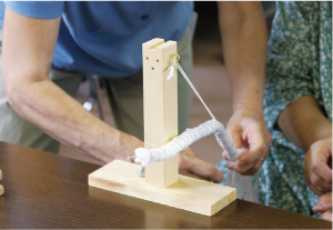 木で作られた固定台。机に固定して使い、絞り台に針をかけて縫います。(写真ではビニールひもを掛け、絞りで使う道具にひもを巻いています)