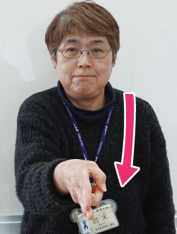 手話通訳者鈴木さんが指文字の「と」を表現しながら、口の前から放物線を描きながら胸の前に下げている写真