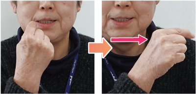 手話通訳者鈴木さんが歯を指さしながら、向かって左から右へ動かしている写真