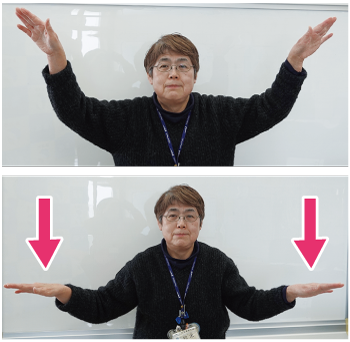 手話通訳者鈴木さんが翼に見立てた両手を上にあげ、下におろす写真