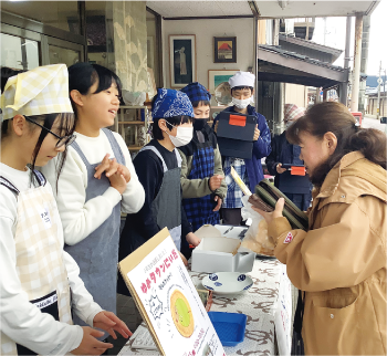 商品を販売する新飯田小学校の児童の写真