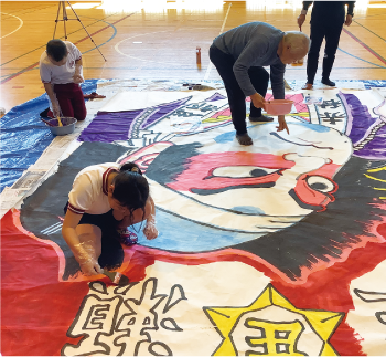 指導者と一緒に凧の色塗りをする庄瀬小学校の児童の写真