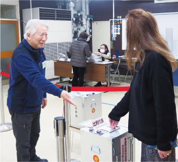 小川さんが選挙会場で案内をしている写真