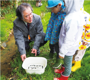 園児と一緒にホタルを放流している写真