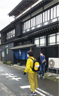 黄色い服を着たまち歩きガイドが白根商店街を案内する写真