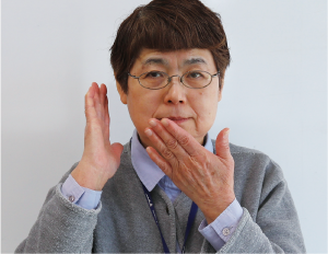 鈴木さんが右手を耳に、左を口に当てる写真