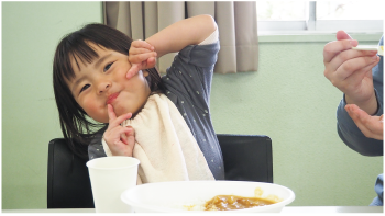 こどもがカレーを食べて笑顔になっている写真