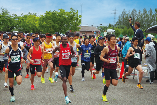 スタート地点から一斉に駆けだすハーフ一般男子の部のランナーたちの写真