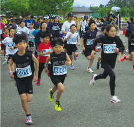 真剣な表情でスタート地点から一斉に駆け出す小学生の部の男子や女子たちの写真