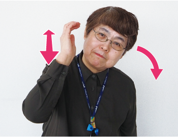指先を曲げた右手を顔の横に持ってきて、首を傾けている写真