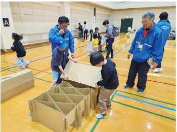 子ども二人で向かい合って段ボールベッドを作っている写真