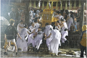 祭り装束に神輿をかついでいる多くの人の写真
