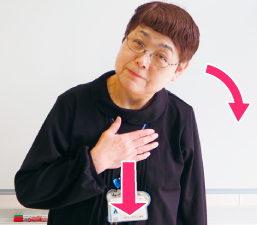 右手を胸に当て、首をかしげる写真