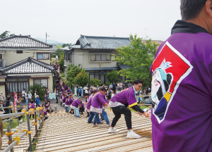 綱を持つ一心助の法被を着た人たちの写真