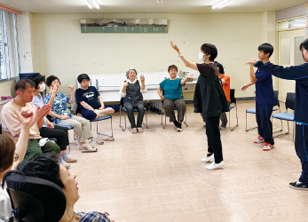 椅子に座っている人たちとその前で立っている人の写真