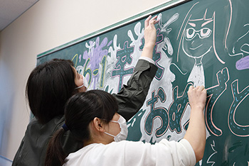 黒板にイラストを描く学生