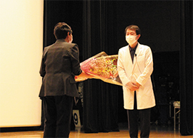 加藤先生が花をもらっている写真