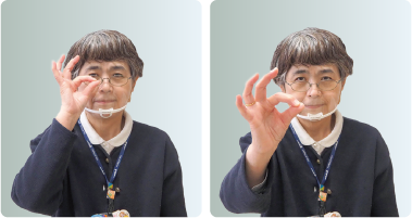 手話通訳者・鈴木さんが右手の親指と人差し指をくっ付けて作った丸からのぞいている写真と、その手を前に出している写真