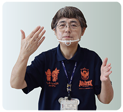 手話通訳・鈴木さんが左手の手のひらを内側に立て、右手は手のひらを内側に顔の前まで上げている写真